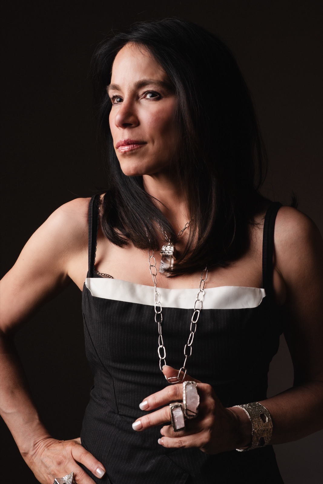 Ana-Lucia in a black dress wearing a chain necklace and silver rings